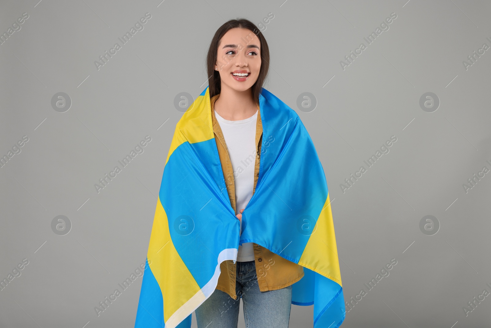 Photo of Young woman with flag of Sweden on light grey background