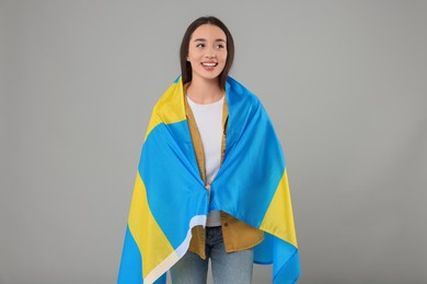 Photo of Young woman with flag of Sweden on light grey background