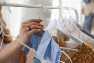 Photo of Woman choosing dress to buy in showroom, closeup