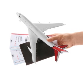 Woman holding toy airplane, passport and tickets on white background, closeup