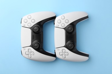Photo of Wireless game controllers on light blue background, flat lay
