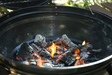 Photo of New modern barbecue grill with burning charcoal outdoors, closeup