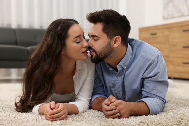 Passionate young couple kissing on soft carpet at home