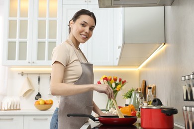 Photo of Woman cooking dinner on cooktop in kitchen