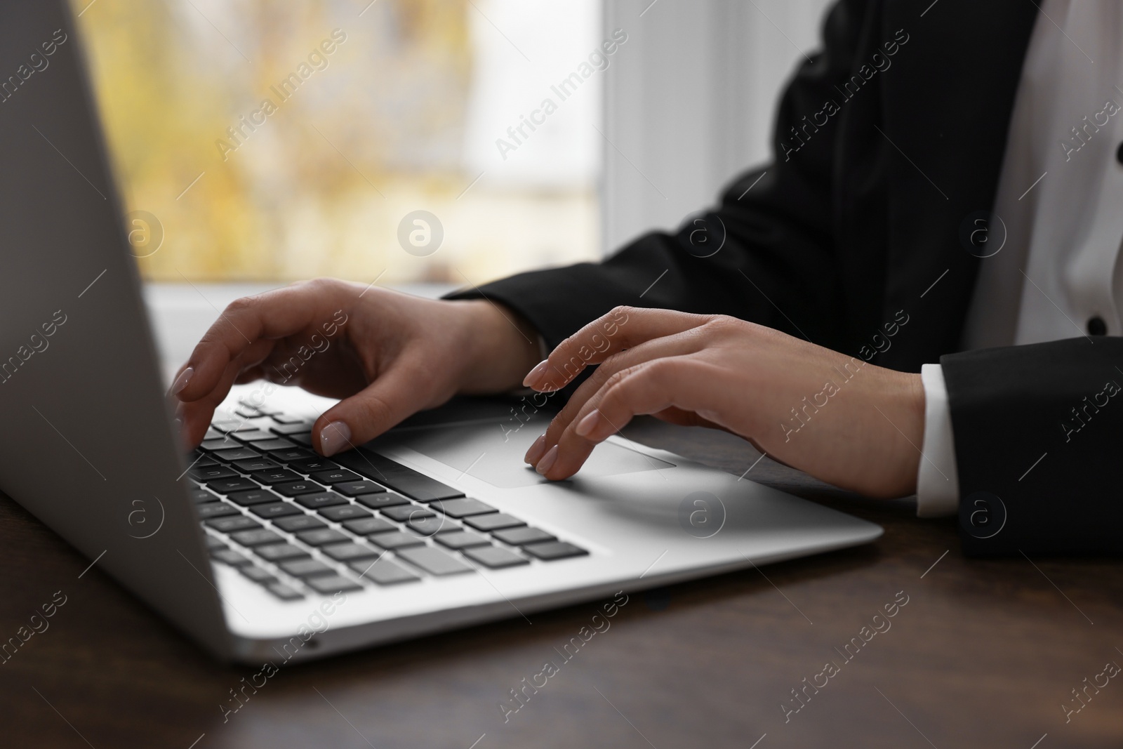 Photo of Woman working on laptop at wooden table closeup. Electronic document management