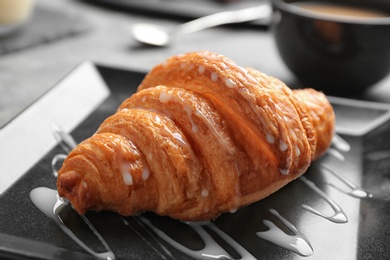 Photo of Plate with tasty croissant and sauce on table, closeup. French pastry