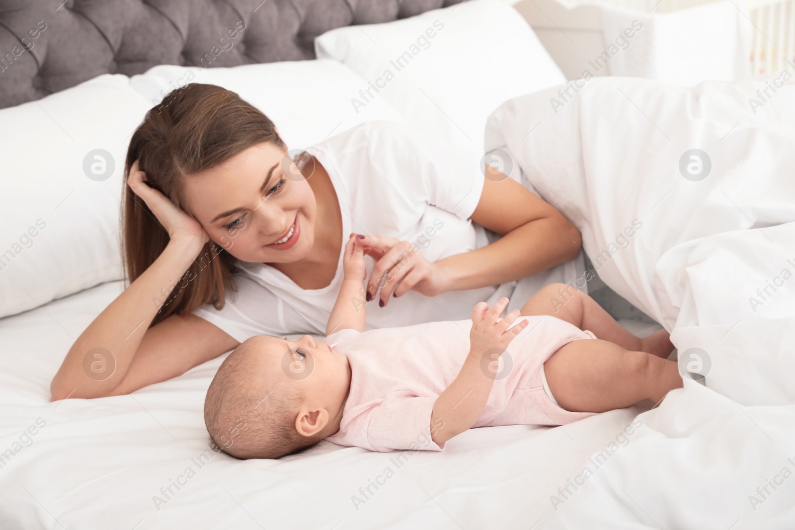 Photo of Portrait of mother with her cute baby lying on bed indoors