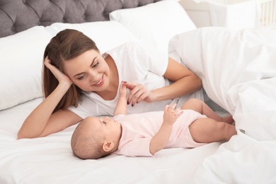 Portrait of mother with her cute baby lying on bed indoors
