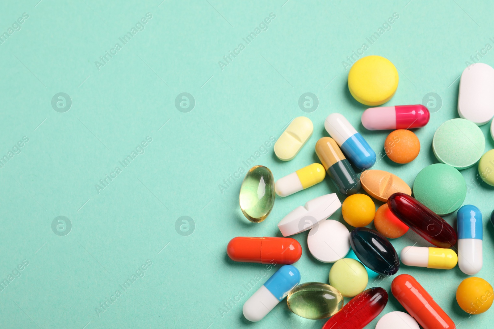 Photo of Many different pills on turquoise background, flat lay. Space for text