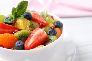 Photo of Delicious fresh fruit salad in bowl on table, closeup. Space for text