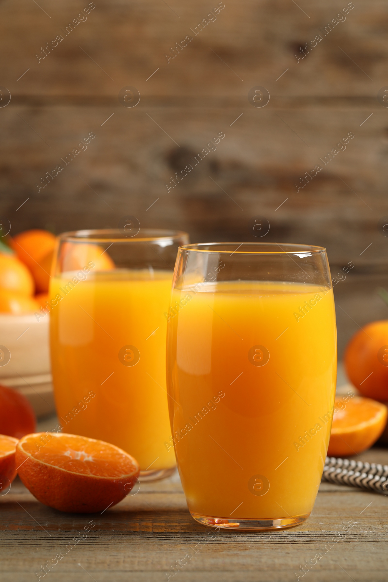 Photo of Glasses of fresh tangerine juice and fruits on wooden table