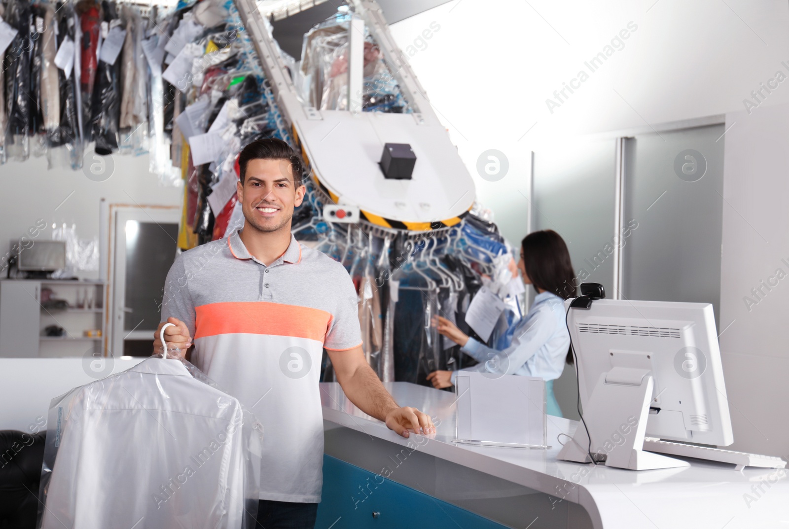 Photo of Happy client with shirt near counter at dry-cleaner's