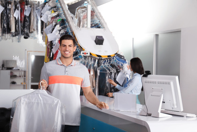 Photo of Happy client with shirt near counter at dry-cleaner's