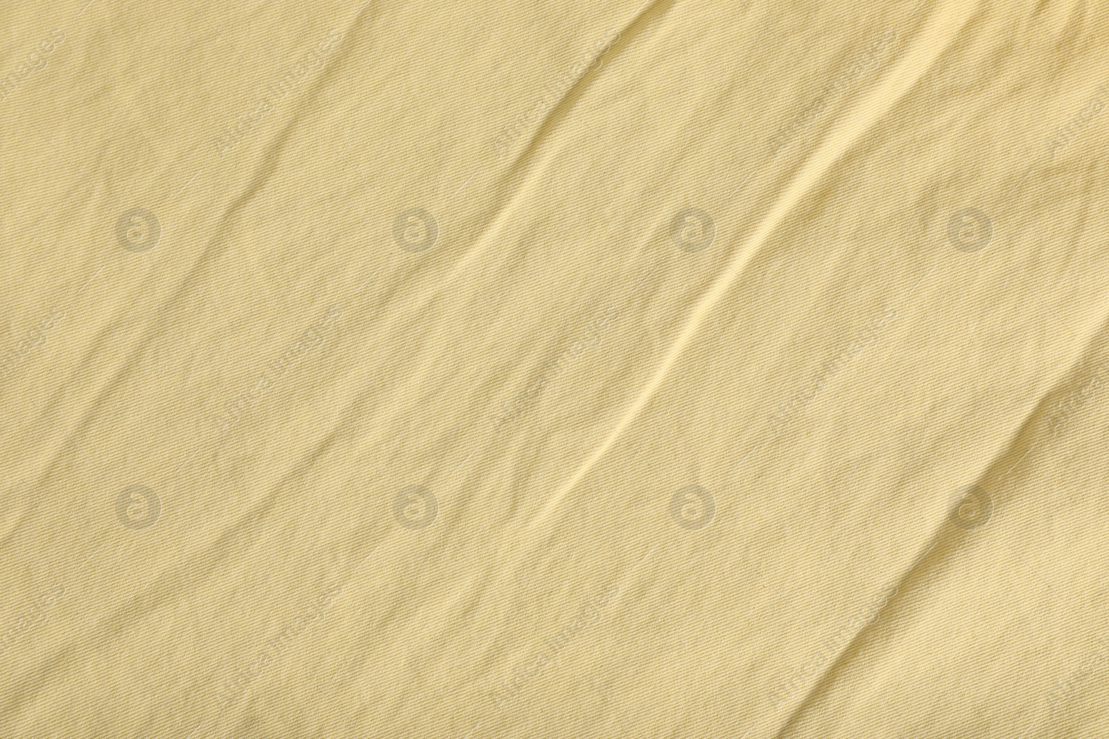 Photo of Crumpled pale yellow fabric as background, top view