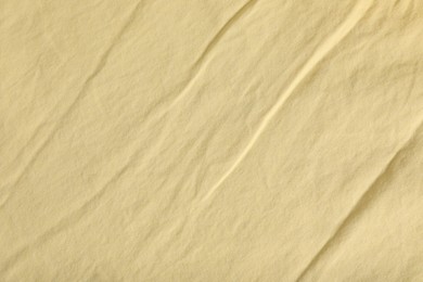 Crumpled pale yellow fabric as background, top view