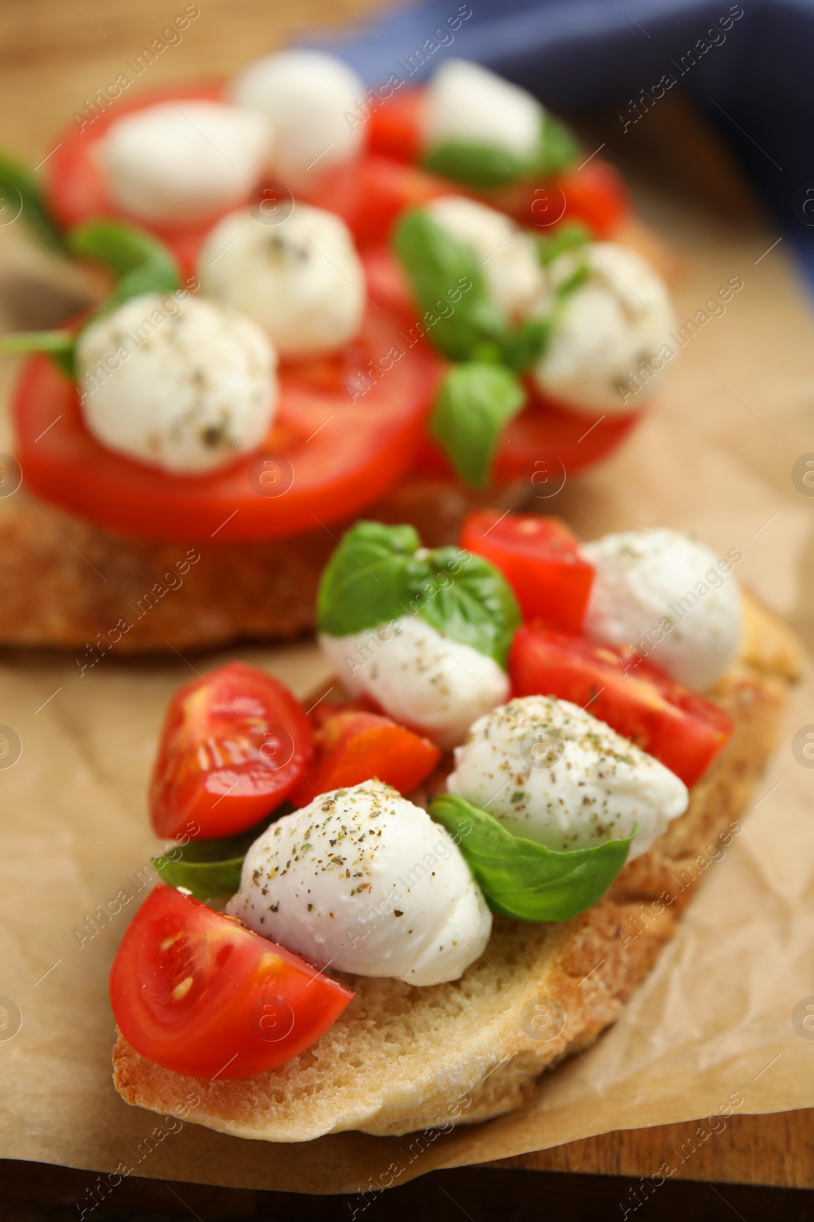 Photo of Delicious sandwiches with mozzarella, fresh tomatoes and basil on parchment