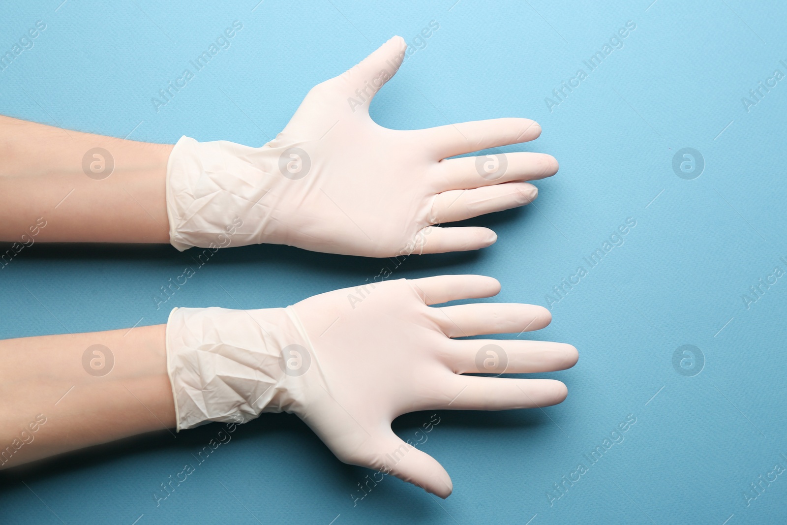 Photo of Person in medical gloves on blue background, closeup of hands