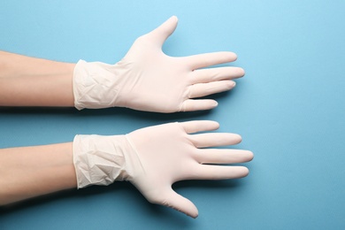 Person in medical gloves on blue background, closeup of hands