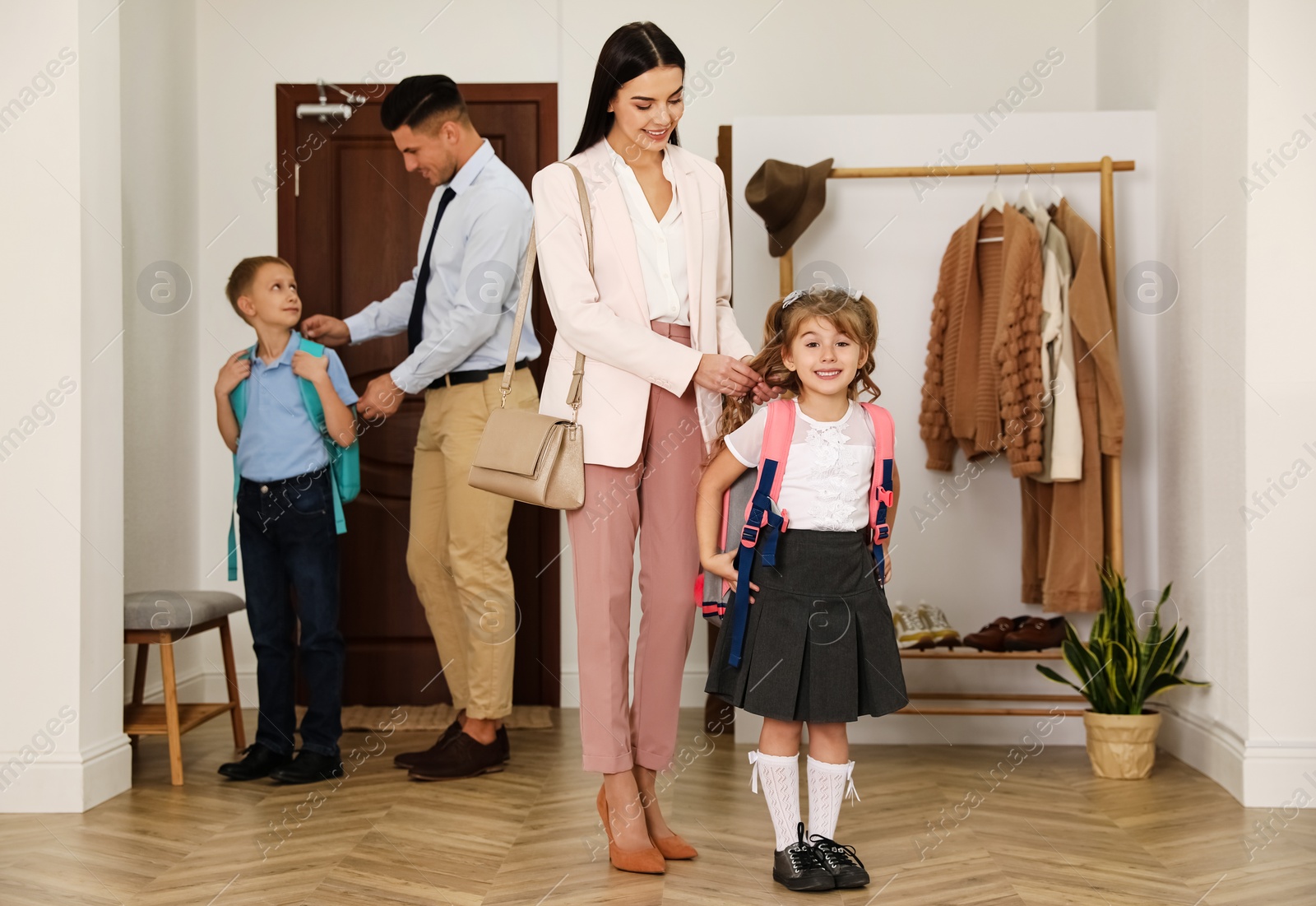 Photo of Parents helping their children get ready for school in hallway