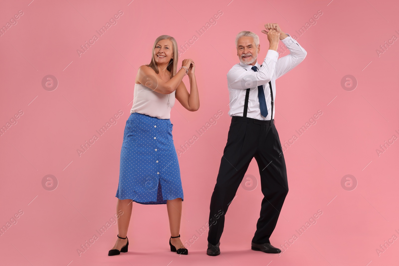 Photo of Senior couple dancing together on pink background