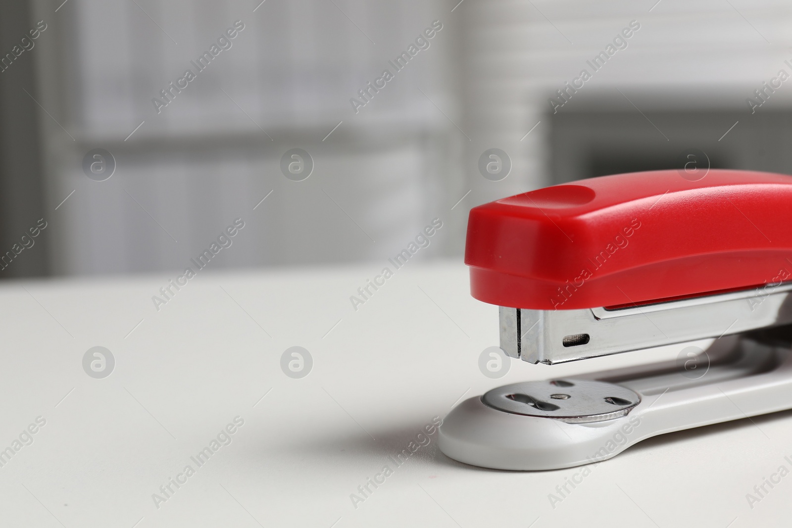 Photo of One stapler on white table, closeup. Space for text