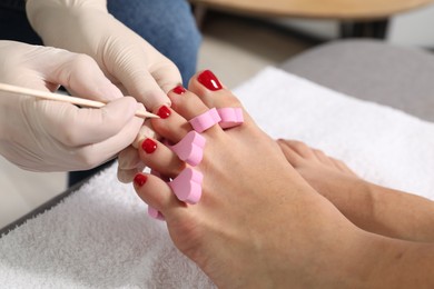 Photo of Pedicurist working with client`s toenails in beauty salon, closeup