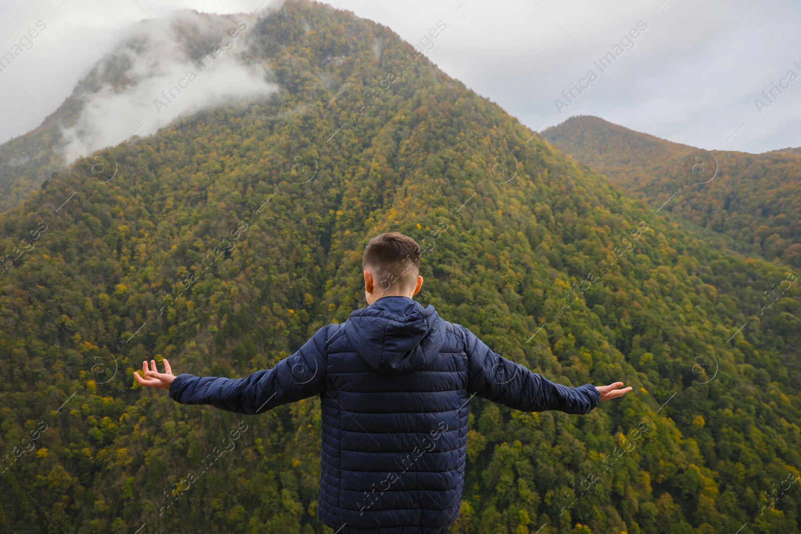 Photo of Man enjoying picturesque mountain landscape, back view