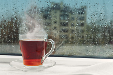 Image of Cup of hot drink near window on rainy day