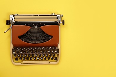 Photo of Vintage typewriter on yellow background, top view. Space for text