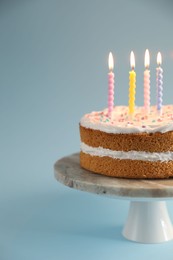 Photo of Tasty cake with colorful candles on light blue background