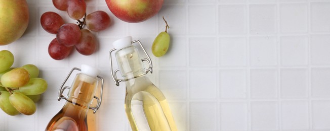 Different types of vinegar and ingredients on light tiled table, flat lay. Space for text