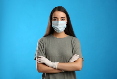 Woman wearing protective face mask and medical gloves on blue background