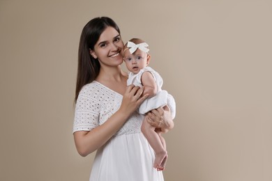 Photo of Beautiful mother with her cute baby on beige background