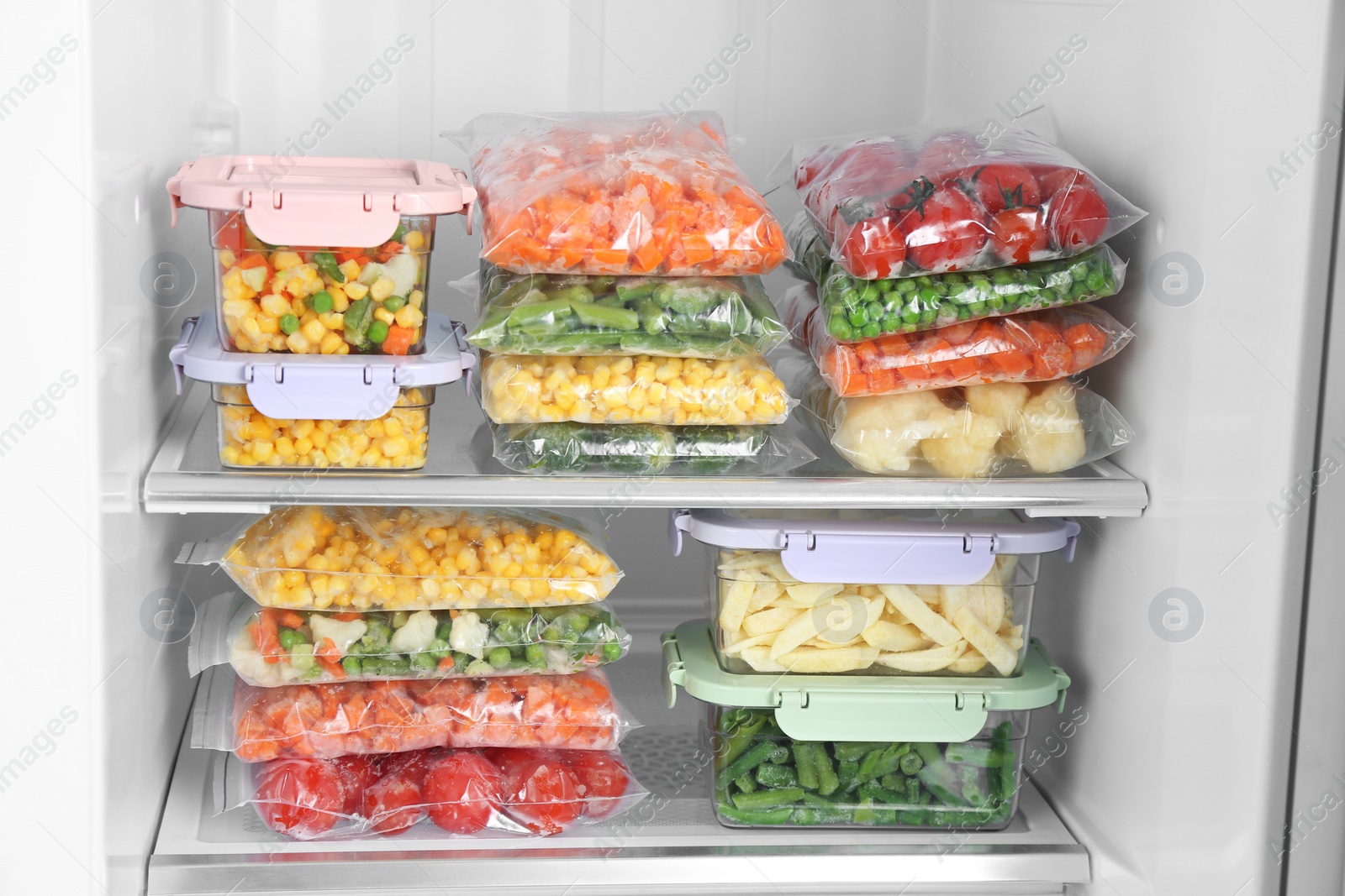 Photo of Plastic bags and containers with different frozen vegetables in refrigerator