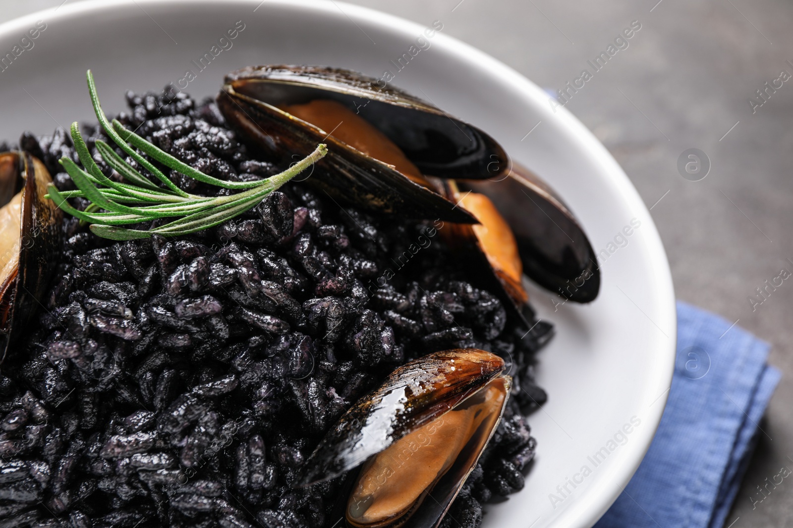 Photo of Delicious black risotto with seafood in bowl on table, closeup