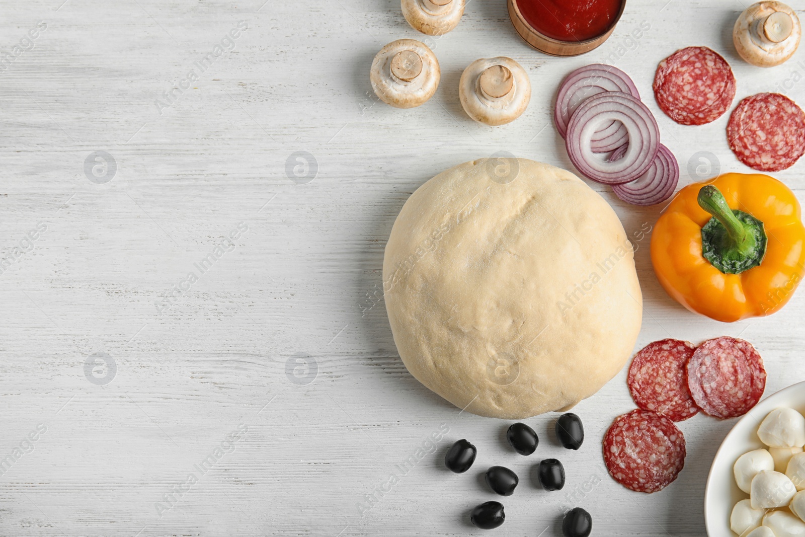 Photo of Flat lay composition with dough and ingredients for pizza on wooden table, space for text