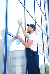 Photo of Male worker washing window glass from outside