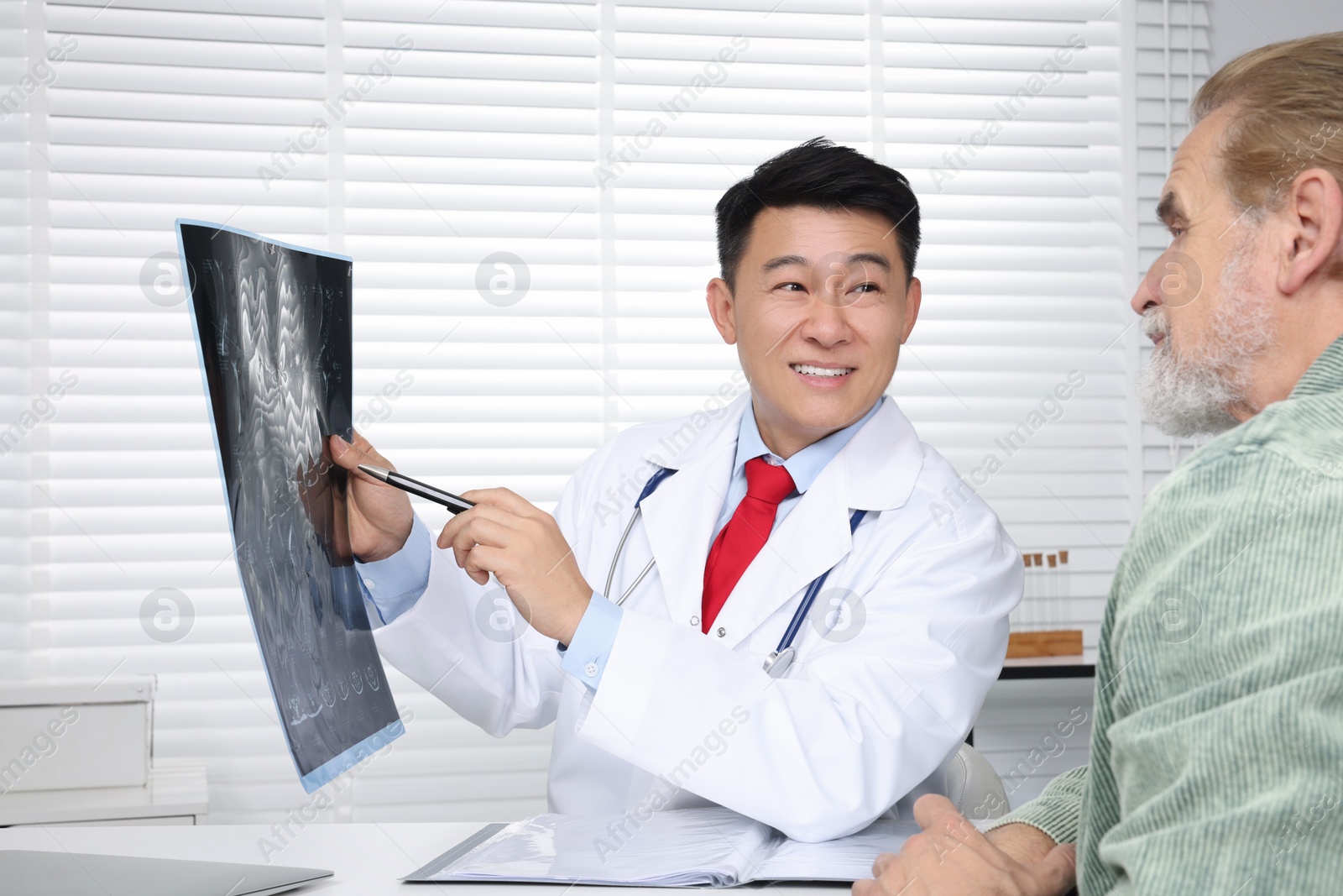 Photo of Happy doctor showing MRI images to senior patient in hospital