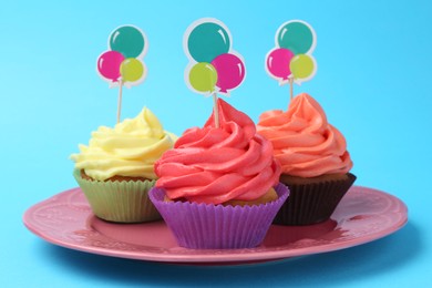 Photo of Delicious cupcakes with bright cream and toppers on light blue background