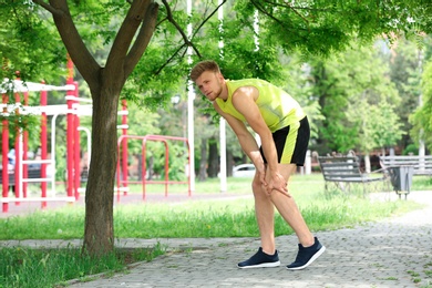 Young man suffering from knee pain in park