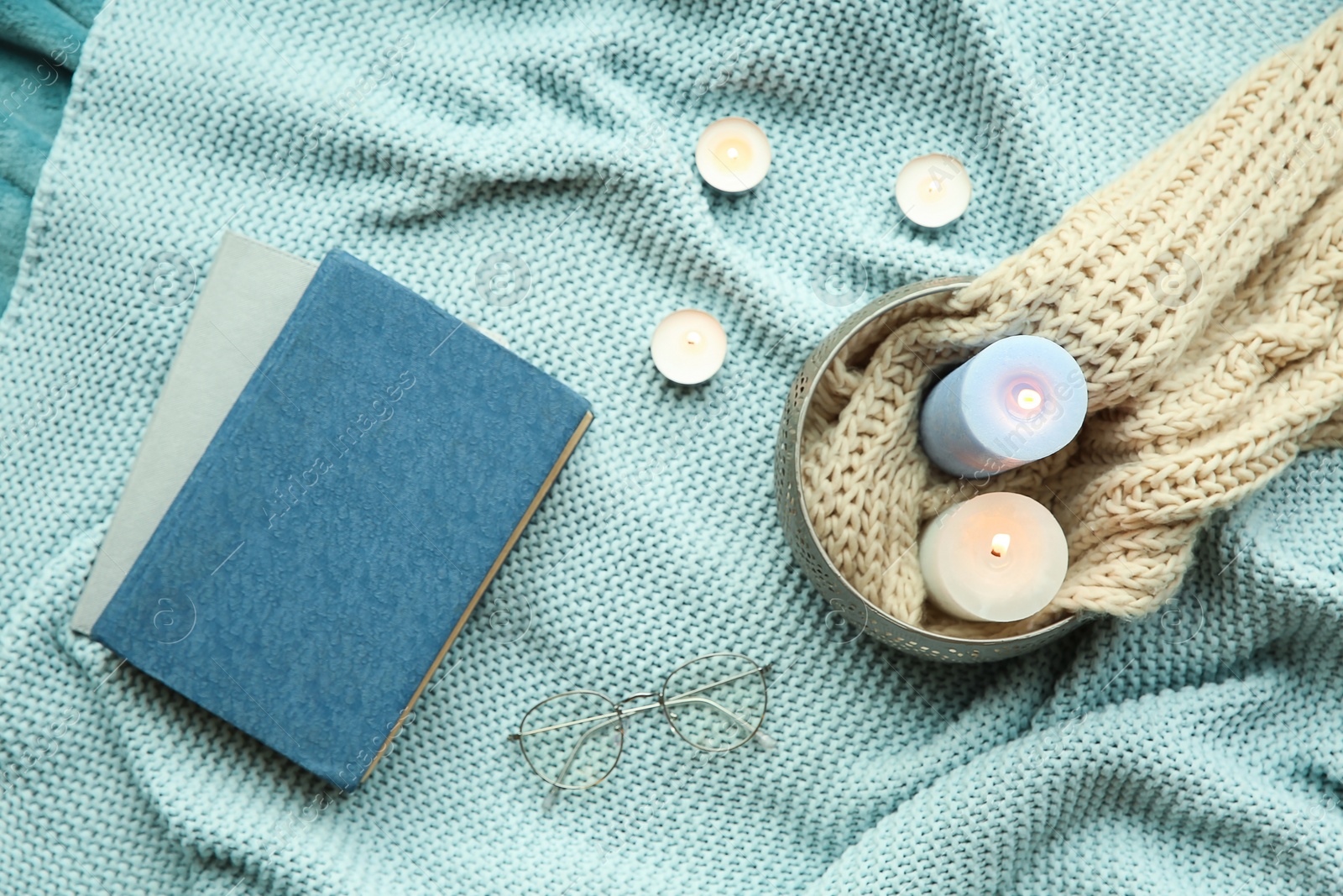 Photo of Beautiful composition with burning candles, eyeglasses and book on fabric, top view