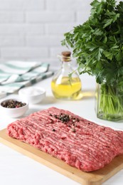 Raw ground meat, spices, oil and parsley on white table