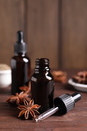 Photo of Anise essential oil and spice on wooden table