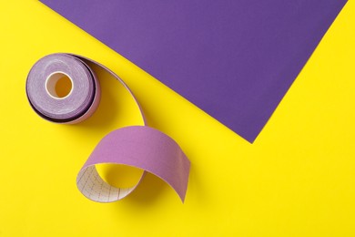 Photo of Bright kinesio tape in roll on color background, top view