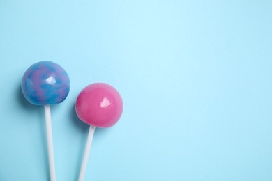 Sticks with colorful lollipops on light blue background, flat lay. Space for text