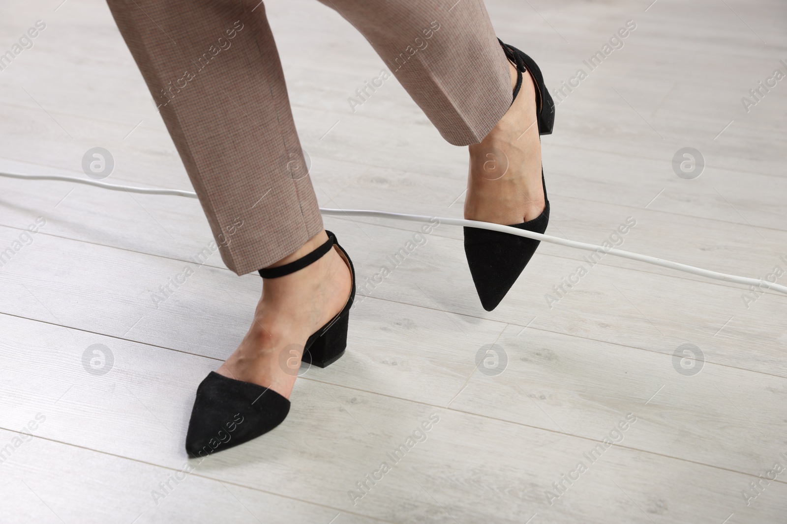 Photo of Woman tripping over cord indoors, closeup view