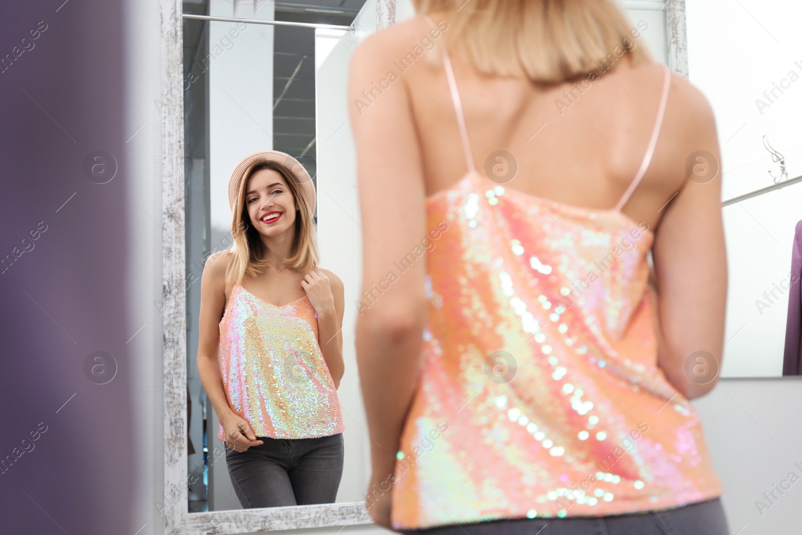 Photo of Young woman trying on clothes in dressing room. Fashion store