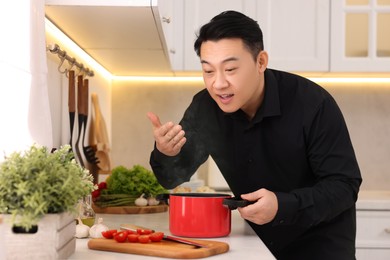 Man smelling dish after cooking at countertop in kitchen