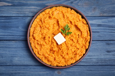 Plate with mashed sweet potatoes on wooden background, top view