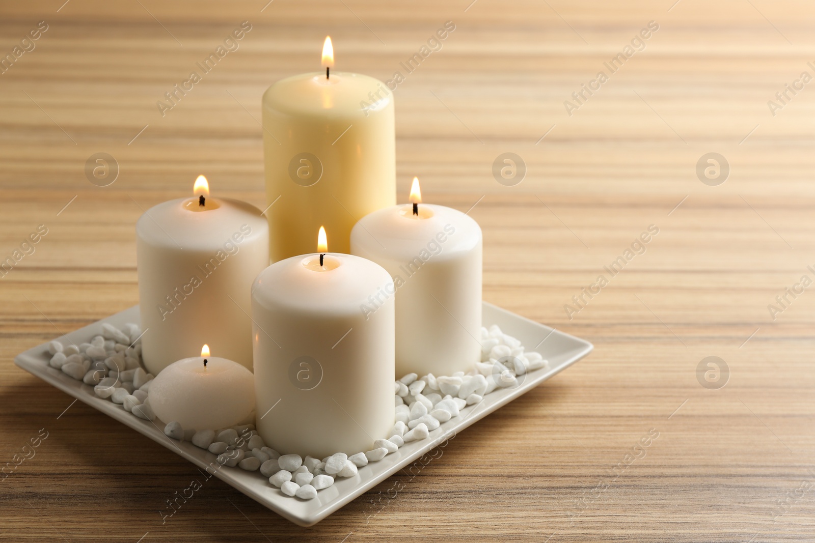 Photo of Plate with burning candles on wooden table. Space for text